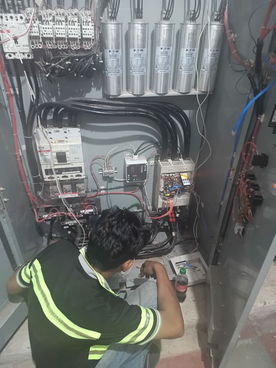 Técnico de POWERTRONICA trabajando en tablero eléctrico industrial con capacitores y VFD